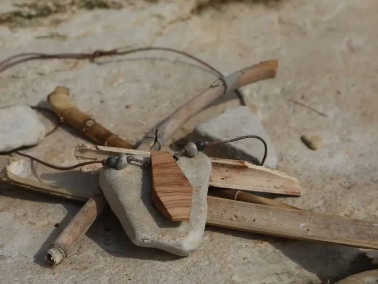Handgefertigte Holzkette aus Stein und Olivenholz an Lederband auf sandigem Untergrund